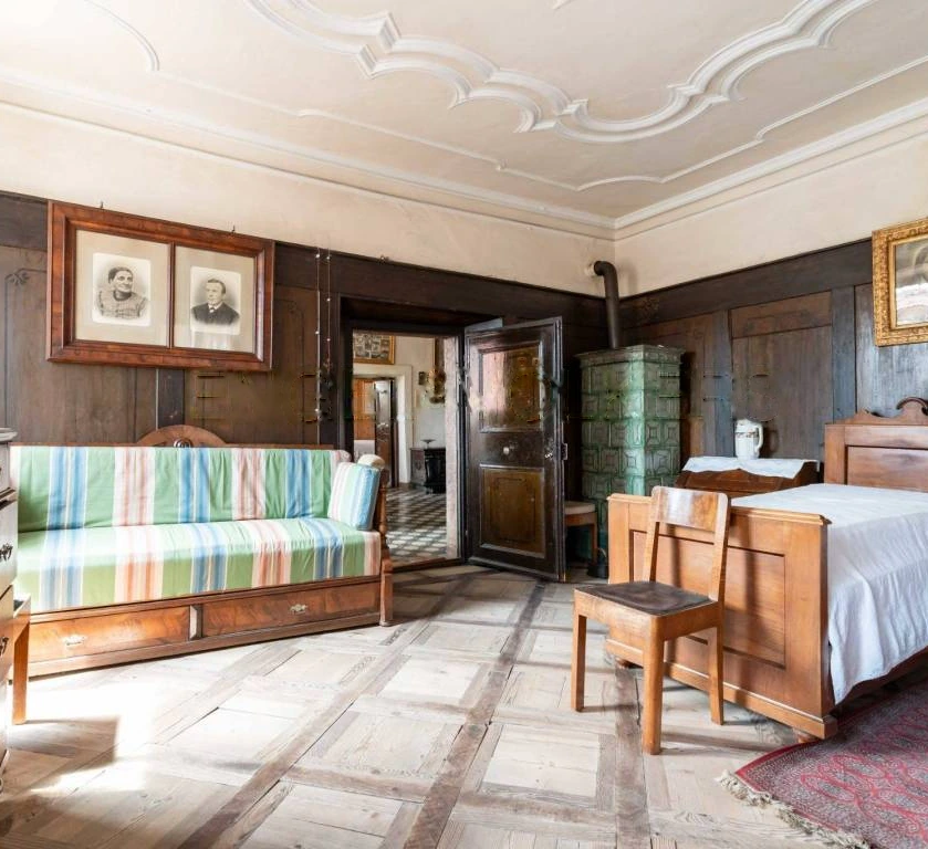 La stanza rivestita in legno con stufa in maiolica e soffitto a stucchi